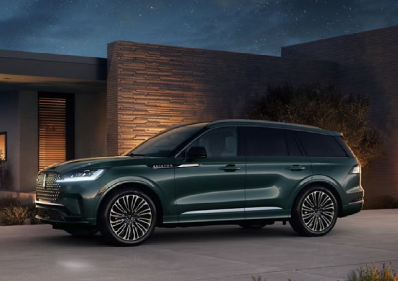 A green 2027 Lincoln Aviator® SUV is parked outside a contemporary home. | Casa Lincoln in El Paso TX
