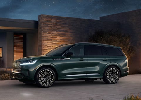 A green 2027 Lincoln Aviator® SUV is parked outside a contemporary home. | Casa Lincoln in El Paso TX