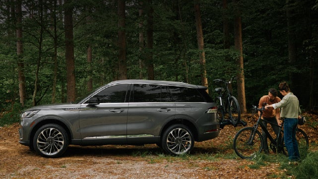 A father and son load e-bikes on a bike rack attached to a 2027 Lincoln Aviator® SUV. | Casa Lincoln in El Paso TX